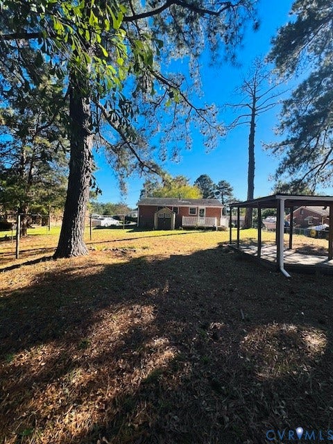 1525 Circle Drive, Petersburg, VA 23803 Expansive backyard featuring mature pine trees, a detached open-air shelter, and a fenced perimeter
