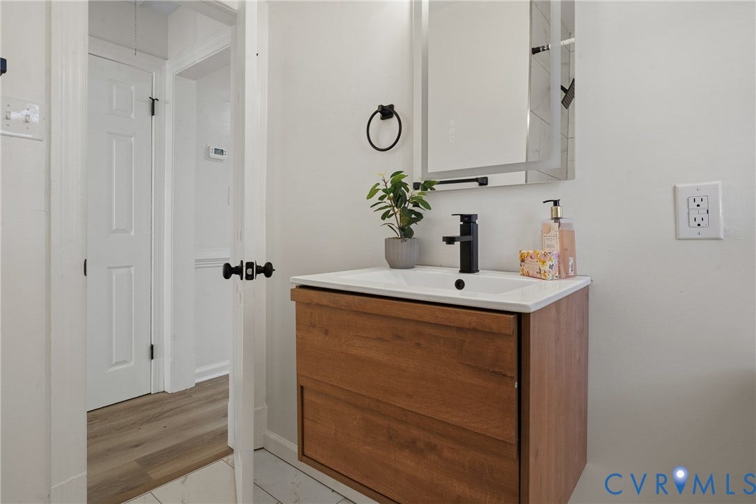 2106 Kenwood Avenue, Henrico, VA 22229 Wall-mounted vanity featuring wood-finish cabinetry, a white integrated rectangular sink, a modern matte black faucet, and a rectangular LED-backlit mirror