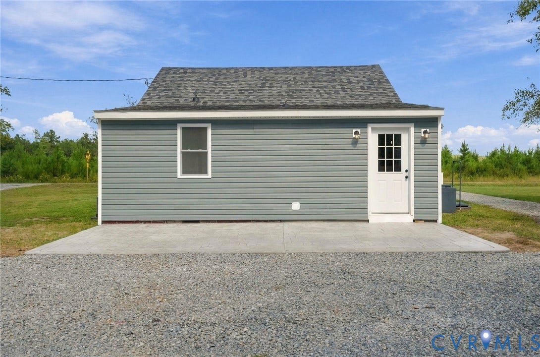 Detached structure featuring blue vinyl siding, a gabled roof with asphalt shingles, a concrete pad entrance, and exterior wall-mounted lighting fixtures
