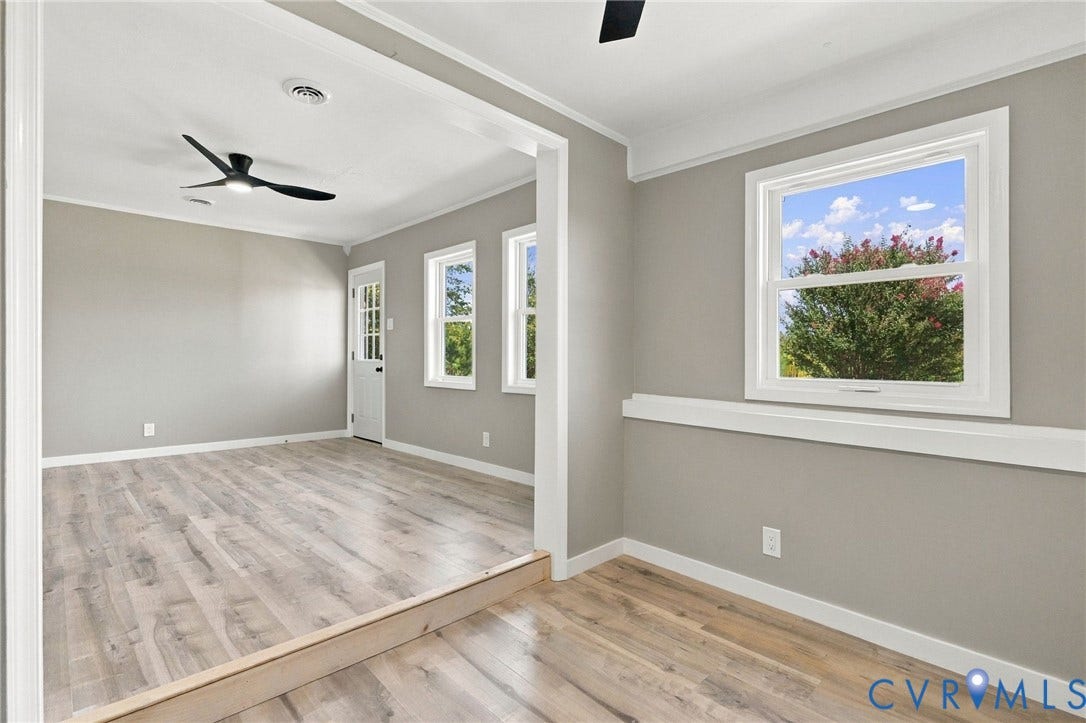 Neutral-toned walls featuring crisp white wainscoting and trim, wood-finish flooring, recessed lighting, and matte black ceiling fans