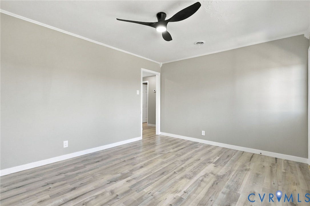 Neutral grey interior walls, wood-finish flooring, and a modern three-blade ceiling fan with integrated lighting
