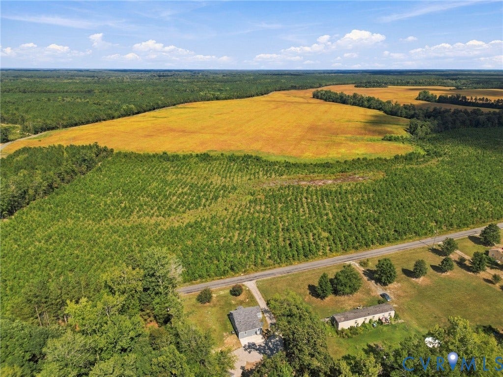 Expansive acreage featuring vast cultivated fields, dense forested areas, and direct road access