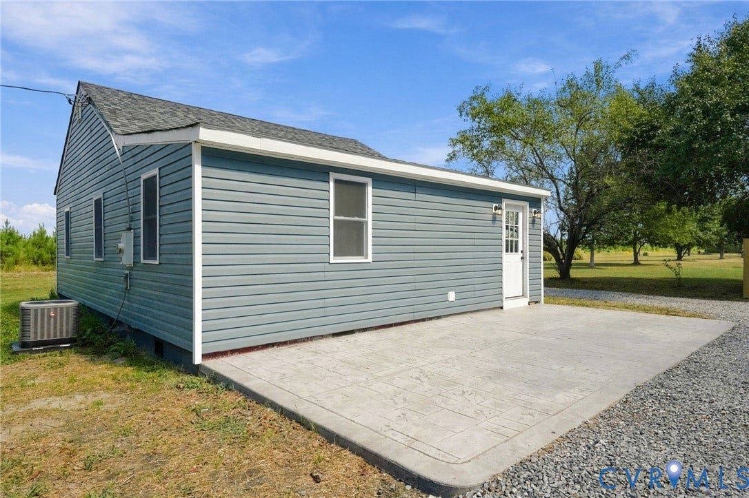 Exterior featuring blue vinyl siding, asphalt shingle roof, and a stamped concrete patio