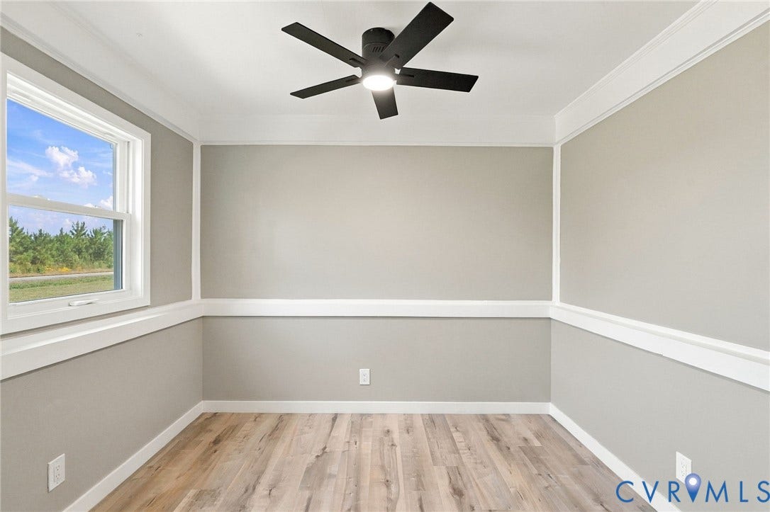 Room featuring wood-finish flooring, white crown molding, chair rail trim, and a ceiling-mounted light fixture