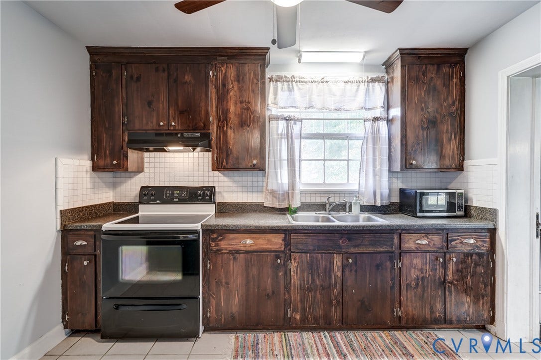 4007 Austin Avenue, Richmond, VA 23222 Kitchen featuring dark wood cabinetry, square tile backsplash, stone-finish countertops, stainless steel double-basin sink, and integrated overhead ceiling fan