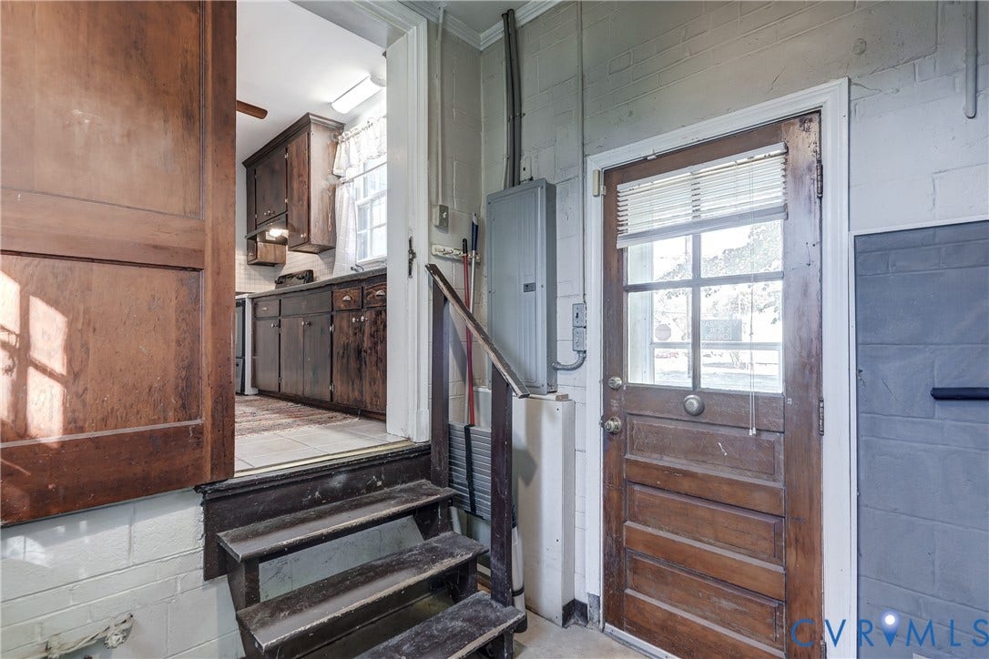 4007 Austin Avenue, Richmond, VA 23222 Exterior wood door featuring a glass pane, wood-finish interior door, stairs with wooden treads and railing, and painted masonry wall finish