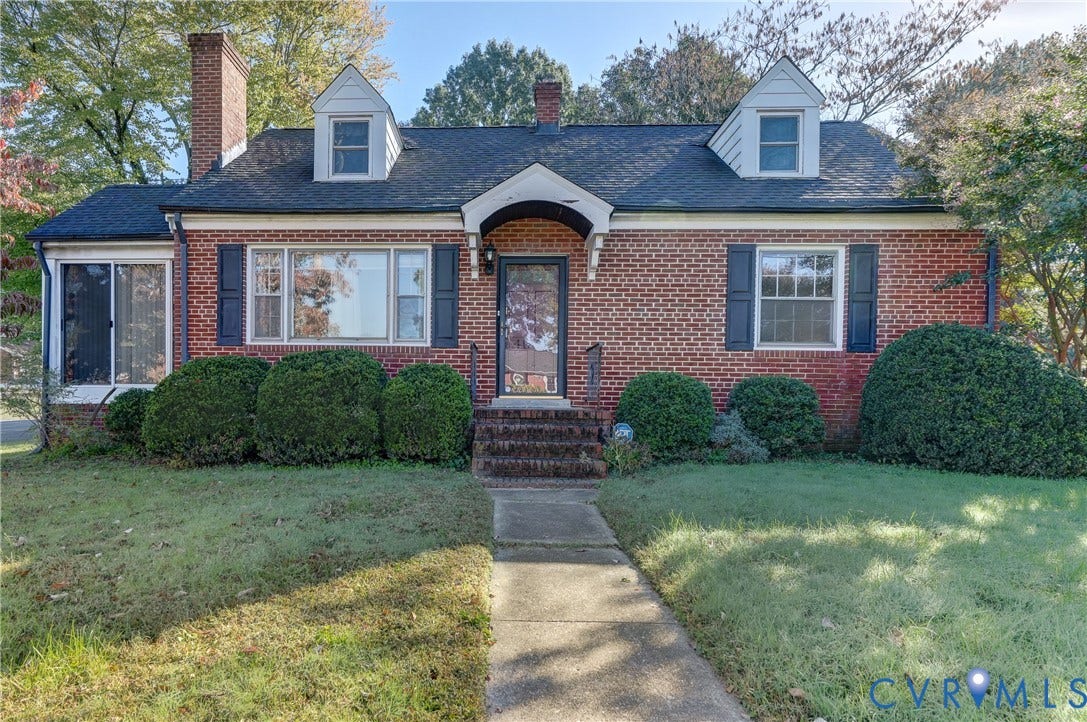 4007 Austin Avenue, Richmond, VA 23222 Brick exterior featuring dual dormer windows, a central arched entry portico, and a chimney stack