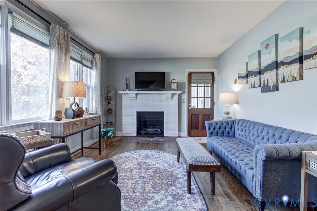 4007 Austin Avenue, Richmond, VA 23222 Painted brick fireplace with a mantel, wood-finish flooring, multi-pane glass door, and large windows