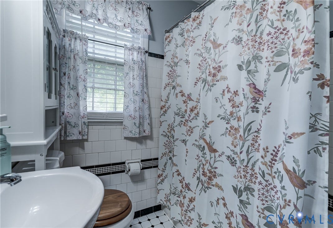 4007 Austin Avenue, Richmond, VA 23222 Bathroom featuring white subway wall tile with black accent detailing, built-in white cabinetry, a porcelain pedestal sink, and black-and-white mosaic tile flooring
