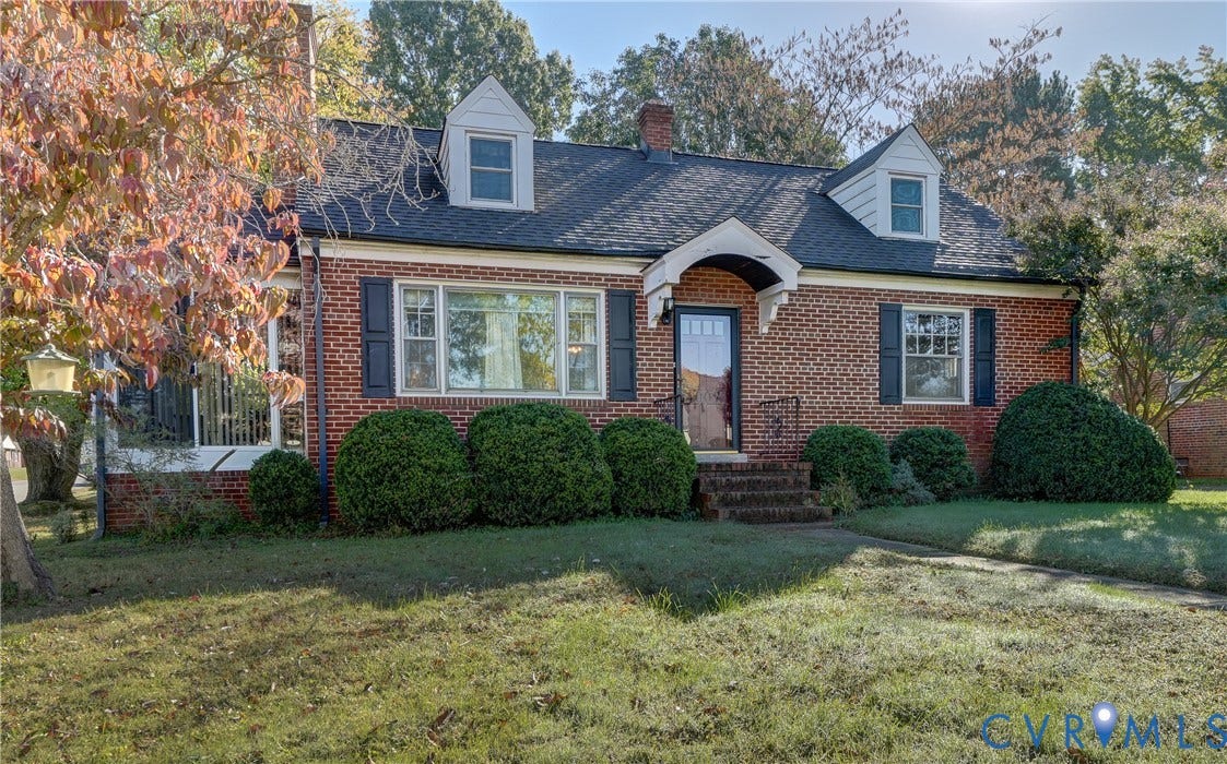 4007 Austin Avenue, Richmond, VA 23222 Brick exterior featuring two dormer windows, an arched covered entryway, shuttered multi-pane windows, and a shingled roof