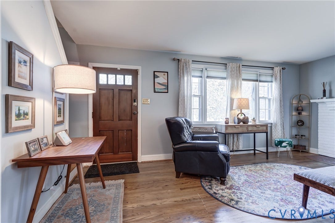 4007 Austin Avenue, Richmond, VA 23222 Living area featuring wood-finish flooring, a multi-paneled wood entry door with glass transom accents, multi-pane windows, and a white brick fireplace surround