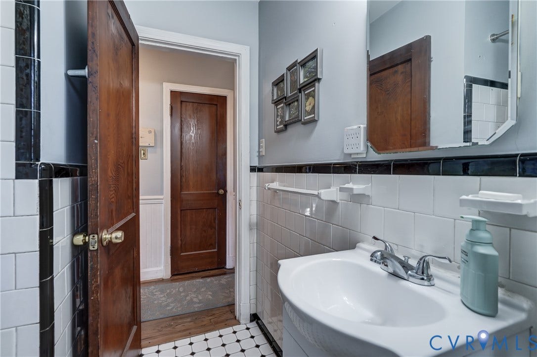 4007 Austin Avenue, Richmond, VA 23222 Bathroom featuring white wall tile with black trim, pedestal sink with dual-handle faucet, checkered tile flooring, and solid wood-finish doors
