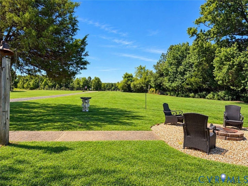 5424 Bellswood Drive, Mechanicsville, VA 23111 Expansive grounds featuring a manicured lawn, stone-surrounded fire pit, concrete pathway, and mature tree canopy