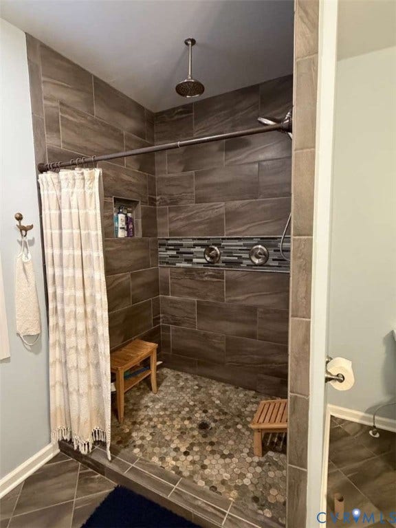 5424 Bellswood Drive, Mechanicsville, VA 23111 Walk-in shower featuring large-format wall tile, a recessed niche, a decorative mosaic tile accent border, a ceiling-mounted rainfall showerhead, and a stone pebble floor