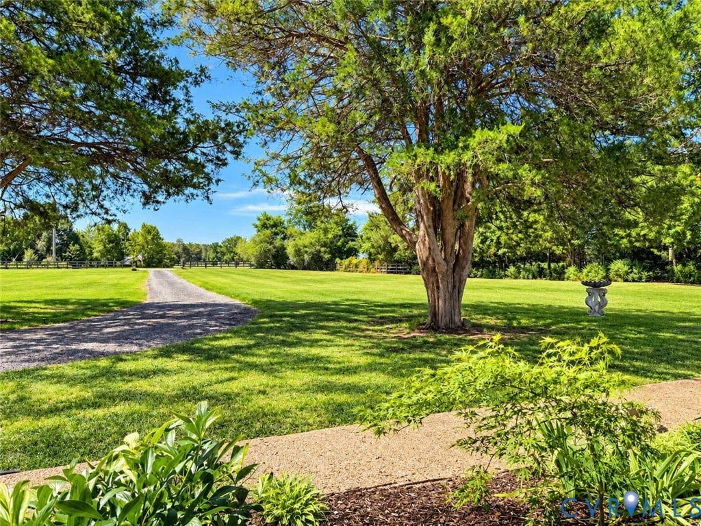 5424 Bellswood Drive, Mechanicsville, VA 23111 Expansive grounds featuring a gravel driveway, mature trees, manicured lawn, and stone garden decor