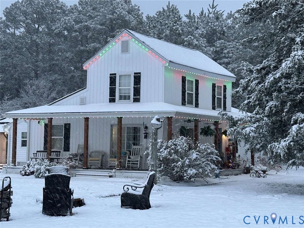 5424 Bellswood Drive, Mechanicsville, VA 23111 Two-story farmhouse exterior featuring white board-and-batten siding, black shutters, a wrap-around covered porch with wood-finished columns, and a peaked roofline