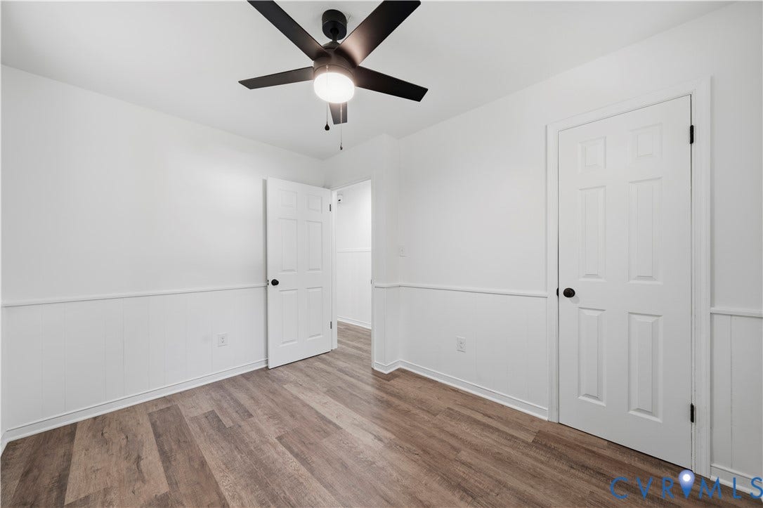 3622 New Bethel Road, Meherrin, VA 23954 Room featuring wood-finish flooring, wainscoting, matte black door hardware, and a ceiling-mounted light fixture with a fan