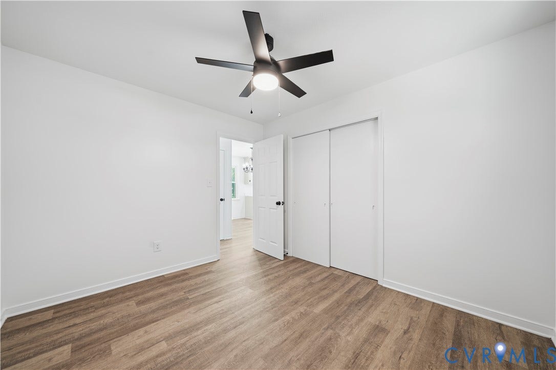 3622 New Bethel Road, Meherrin, VA 23954 Room featuring wood-finish flooring, a matte black multi-blade ceiling fan with integrated lighting, and a closet with sliding doors