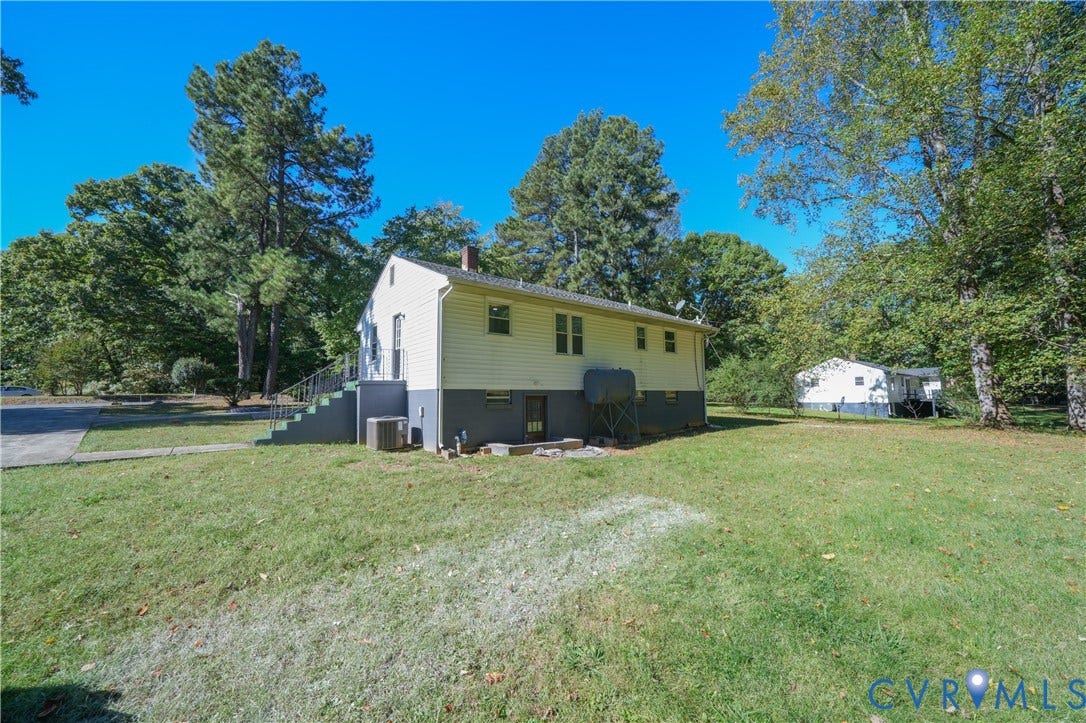 3622 New Bethel Road, Meherrin, VA 23954 Exterior featuring light-colored horizontal siding, a concrete foundation, mature trees, and an expansive grass lawn