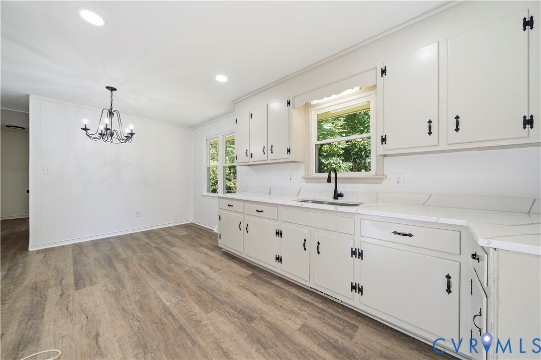 3622 New Bethel Road, Meherrin, VA 23954 Kitchen featuring cabinetry with matte black hardware, stone-finish countertops, an undermount sink with a matte black faucet, wood-finish flooring, and a multi-arm chandelier