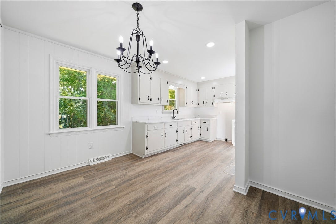 3622 New Bethel Road, Meherrin, VA 23954 Kitchen featuring wood-finish flooring, white cabinetry, a matte black faucet, and a six-light iron chandelier