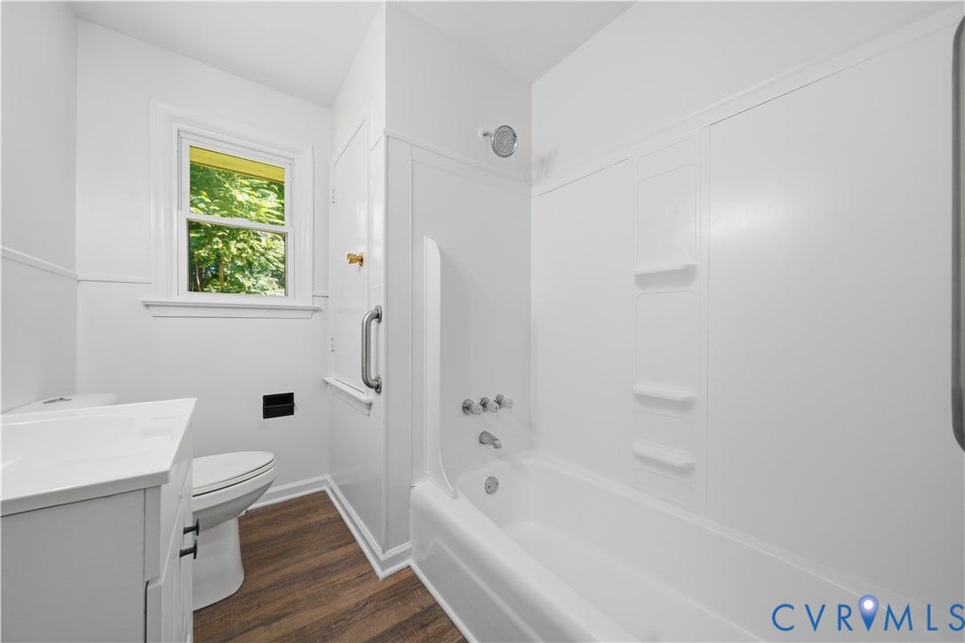 3622 New Bethel Road, Meherrin, VA 23954 Bathroom featuring wood-finish flooring, white vanity with integrated sink, composite tub surround, and fixed metal grab bar