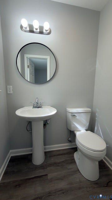 510 Old Town Drive, Ellerslie, Colonial Heights, VA 23834 Pedestal sink with a polished chrome faucet, round wall-mounted mirror with a dark frame, three-light vanity fixture, and wood-finish flooring