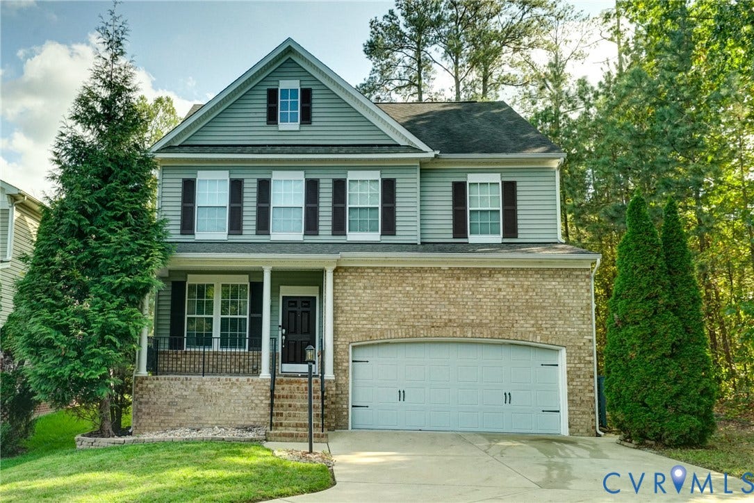 8909 Hollycroft Court, Mechanicsville, VA 23116 Two-story exterior featuring a mix of horizontal lap siding and lower-level brick masonry, front porch with decorative railing, and attached two-car garage