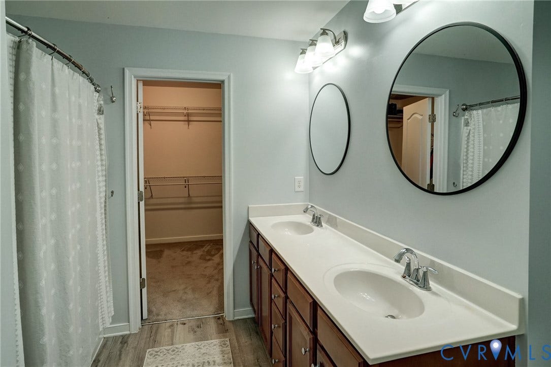 8909 Hollycroft Court, Mechanicsville, VA 23116 Double vanity with a solid-surface countertop, dual undermount sinks, round wall mirrors, and wood-finish cabinetry