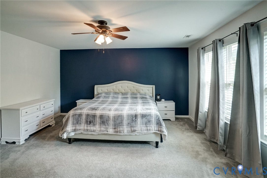 8909 Hollycroft Court, Mechanicsville, VA 23116 Room featuring wall-to-wall carpeting, a deep navy accent wall, and a multi-blade ceiling fan with integrated light fixture
