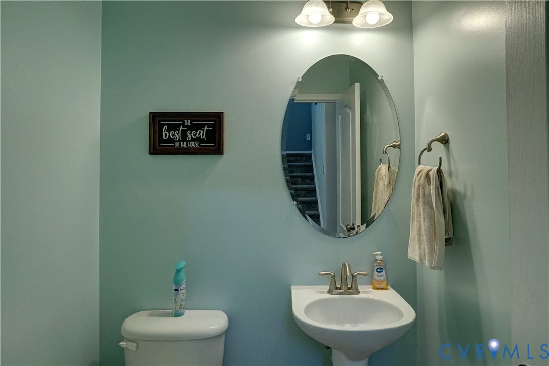 8909 Hollycroft Court, Mechanicsville, VA 23116 Wall-mounted oval mirror, pedestal sink with dual-handle faucet, and two-light vanity fixture