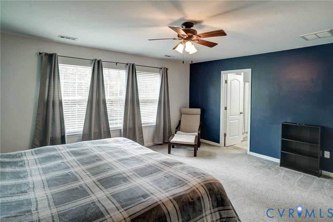 8909 Hollycroft Court, Mechanicsville, VA 23116 Room featuring neutral carpeting, a dark accent wall, a central ceiling fan with integrated lighting, and multiple windows with blinds
