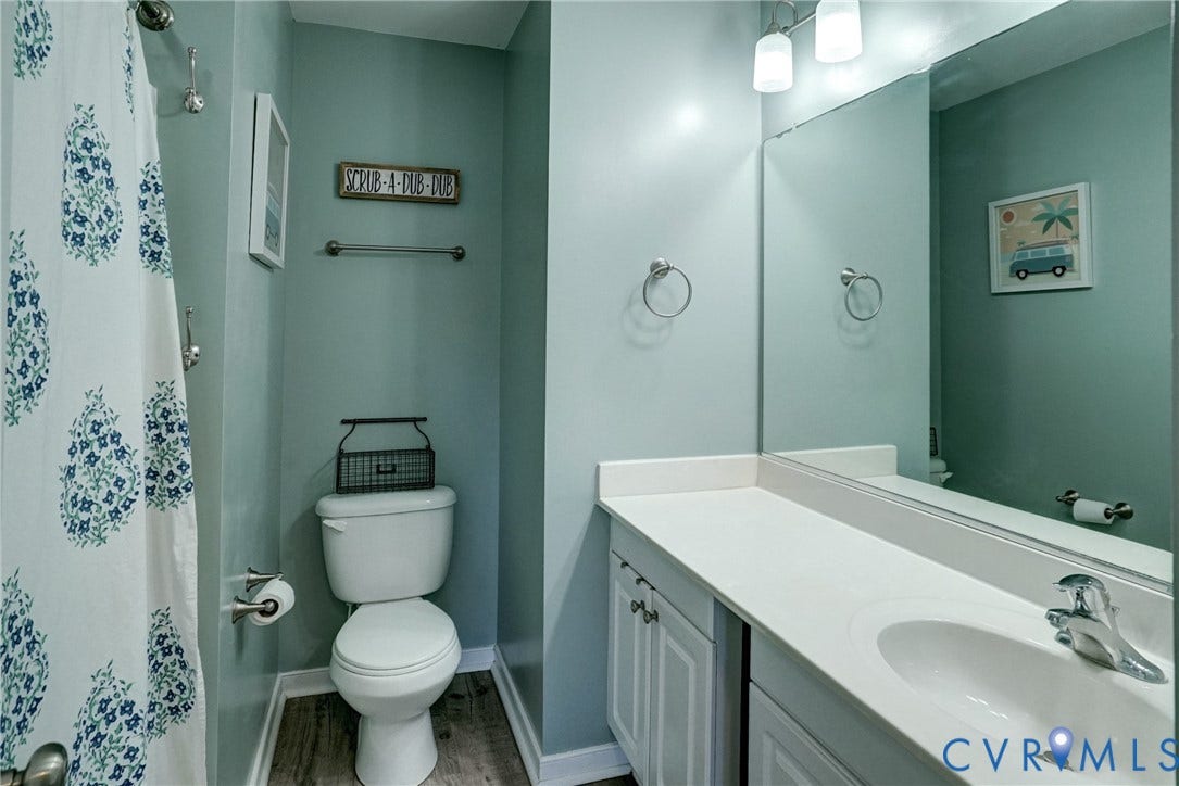 8909 Hollycroft Court, Mechanicsville, VA 23116 Bathroom featuring a vanity with a white countertop and integrated sink, a full-width wall mirror, wood-finish flooring, and a combined tub and shower area