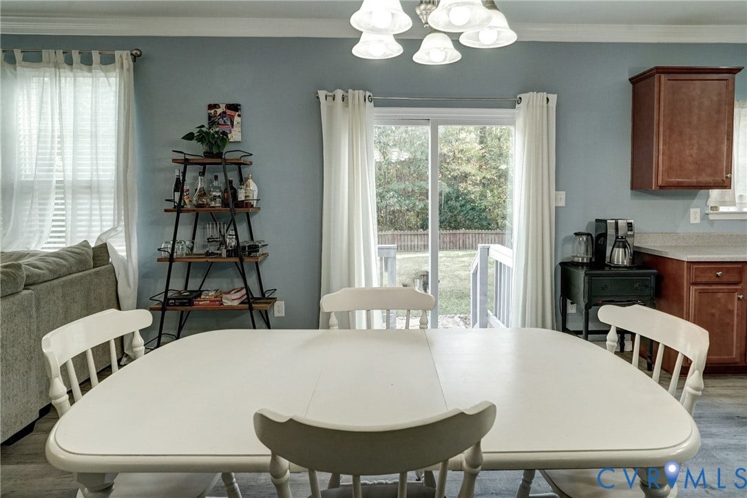 8909 Hollycroft Court, Mechanicsville, VA 23116 Dining area featuring glass sliding doors, wood-finish cabinetry, crown molding, and a five-light chandelier