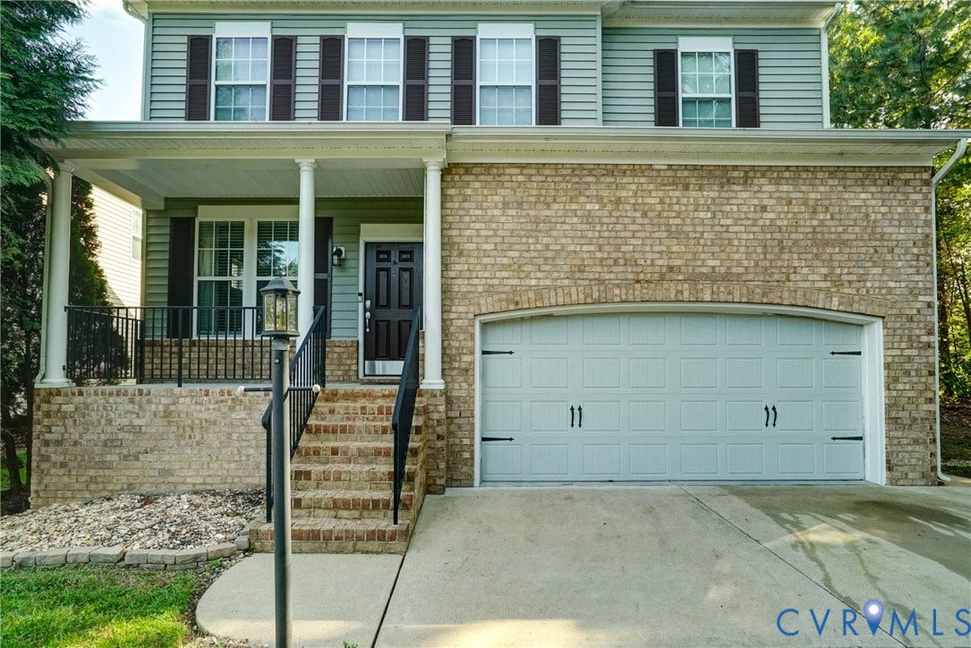8909 Hollycroft Court, Mechanicsville, VA 23116 Two-story exterior featuring a brick facade with horizontal siding, a covered front porch with a black metal railing, and an attached two-car garage