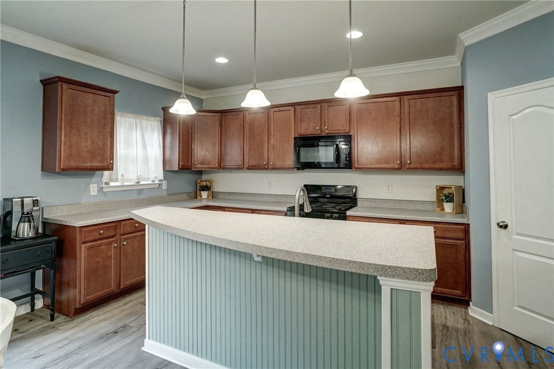 8909 Hollycroft Court, Mechanicsville, VA 23116 Kitchen featuring wood cabinetry, solid-surface countertops, beadboard-paneled breakfast bar, recessed lighting, and three hanging pendant lights