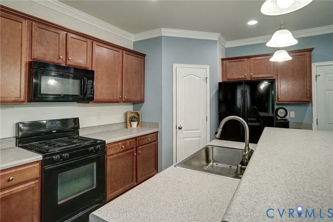 8909 Hollycroft Court, Mechanicsville, VA 23116 Kitchen featuring wood cabinetry, solid-surface countertops, black integrated appliances, stainless steel undermount sink with arched faucet, and crown molding