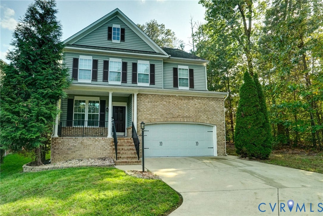 8909 Hollycroft Court, Mechanicsville, VA 23116 Two-story residence featuring a brick and horizontal siding exterior, attached two-car garage, front porch with metal railing, and decorative window shutters