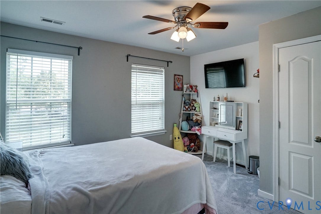 8909 Hollycroft Court, Mechanicsville, VA 23116 Neutral-toned interior featuring carpeted flooring, two windows with horizontal blinds, a ceiling fan with integrated lighting, and a six-panel door