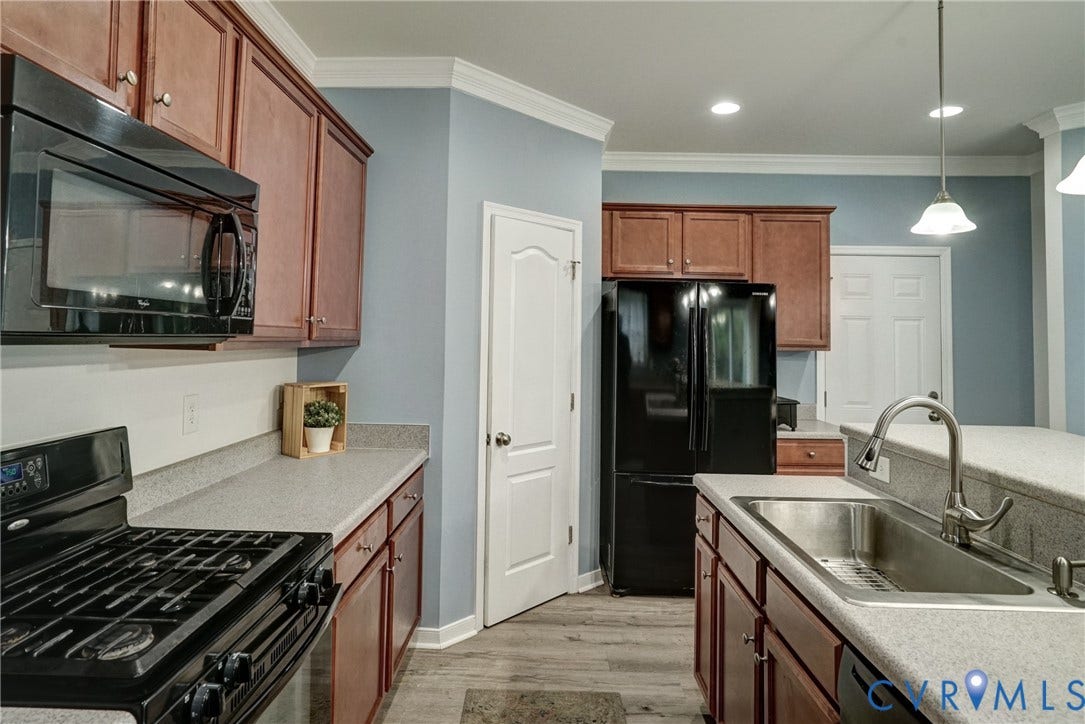 8909 Hollycroft Court, Mechanicsville, VA 23116 Kitchen featuring stained cabinetry, stone-composite countertops, stainless steel sink with pull-down faucet, black appliance suite, and wood-finish flooring