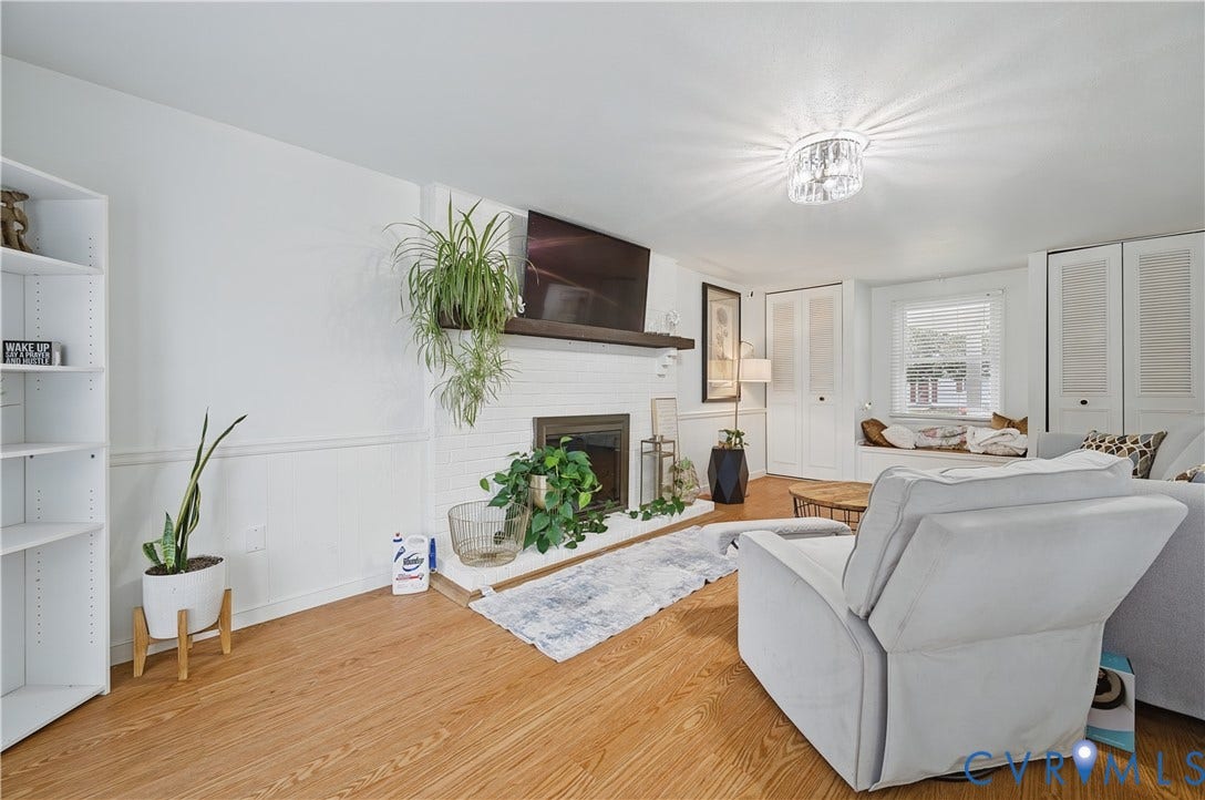 1101 Arch Hill Drive, Chesterfield, VA 23236 Living area featuring wood-finish flooring, a painted brick fireplace with a wood mantel, built-in shelving, a recessed window seat, and louvered-door cabinetry