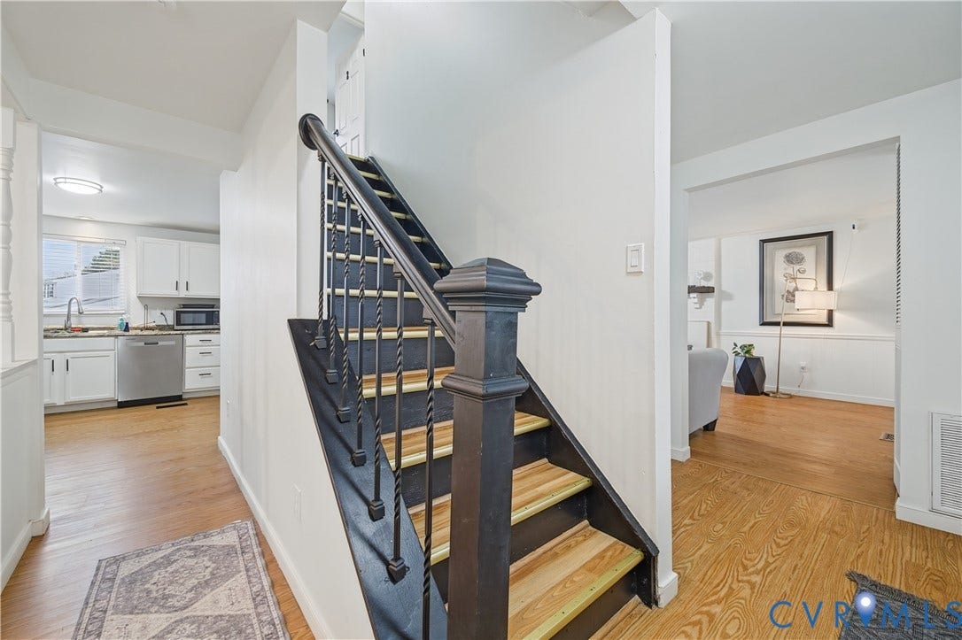 1101 Arch Hill Drive, Chesterfield, VA 23236 Staircase featuring wood-finish treads, a black-painted railing, and a decorative newel post, set against wood-finish flooring