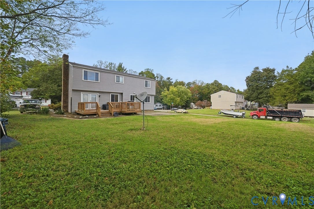 1101 Arch Hill Drive, Chesterfield, VA 23236 Multi-level exterior featuring light gray horizontal siding, a stone chimney, and a wooden deck