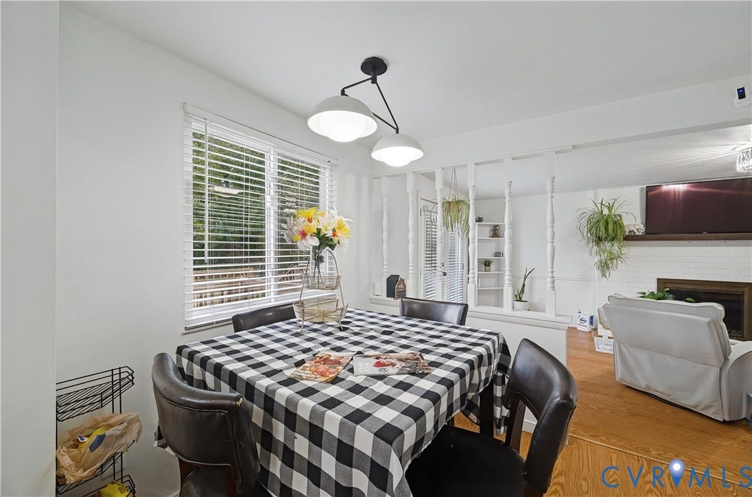 1101 Arch Hill Drive, Chesterfield, VA 23236 Dining area featuring a dual-globe pendant light fixture, horizontal slat window blinds, wood-finish flooring, and a decorative spindle room divider