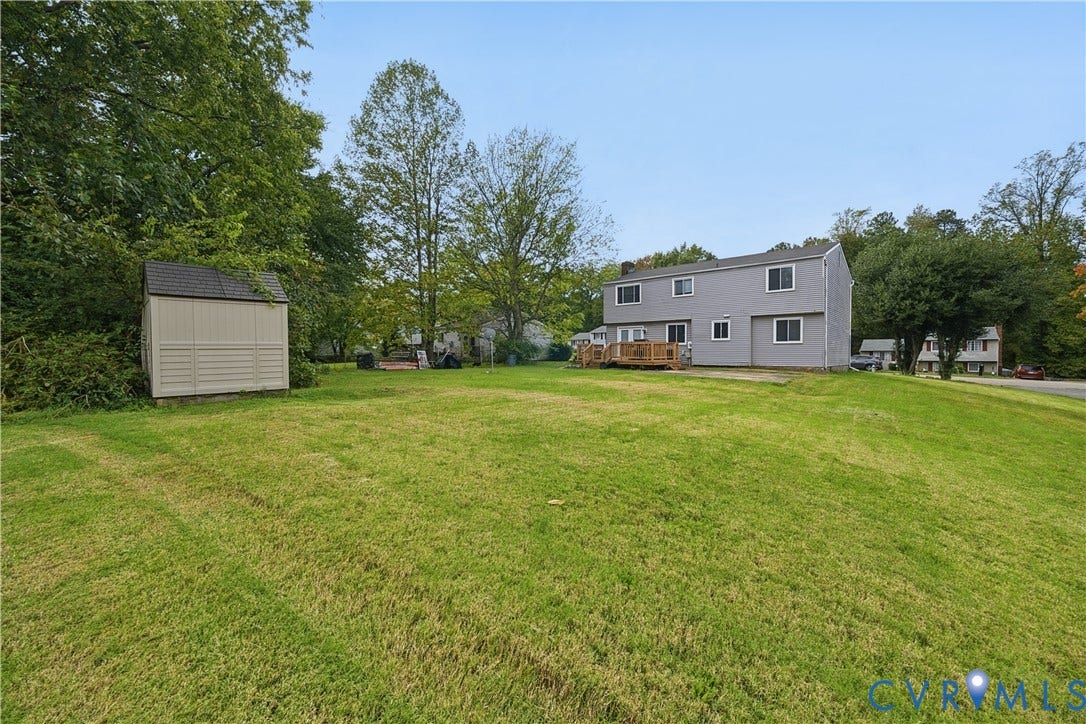1101 Arch Hill Drive, Chesterfield, VA 23236 Expansive backyard featuring a large grass lawn, mature trees, a detached storage shed, and a wooden deck