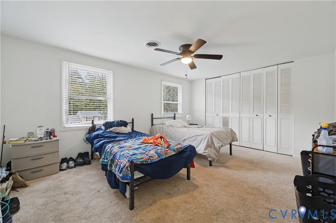 1101 Arch Hill Drive, Chesterfield, VA 23236 Neutral-toned room featuring wall-to-wall carpeting, multiple windows with blinds, a ceiling fan with integrated lighting, and built-in closet storage with louvered doors