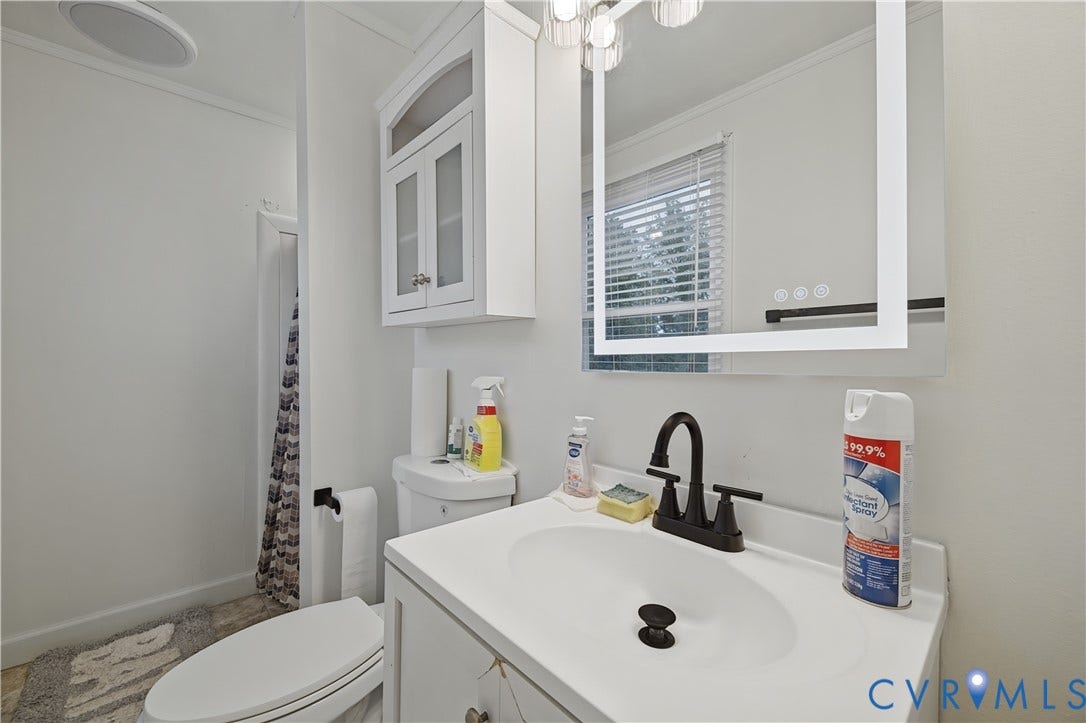 1101 Arch Hill Drive, Chesterfield, VA 23236 Bathroom vanity featuring a white cabinet, integrated sink, matte black faucet, and an illuminated wall-mounted mirror with an overhead light fixture and wall-mounted cabinetry