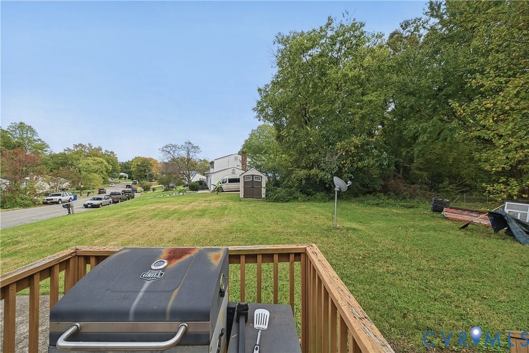 1101 Arch Hill Drive, Chesterfield, VA 23236 Outdoor wooden deck featuring a vertical slat railing, overlooking a sprawling grassy yard with mature trees and a detached storage shed