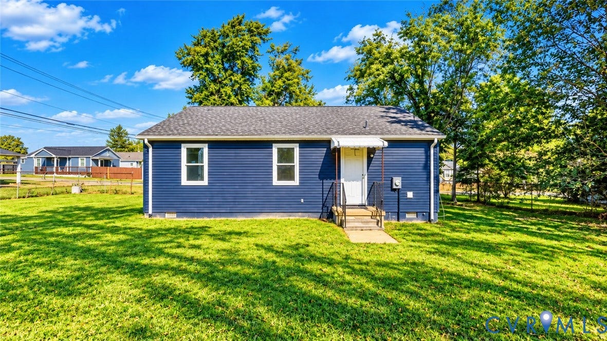 Blue horizontal siding exterior featuring a composite shingle roof, white window trim, and a concrete entrance landing with iron handrails