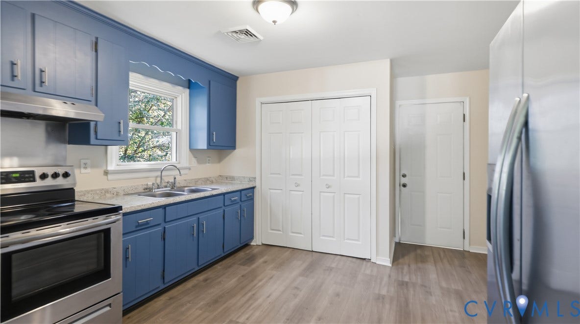 Kitchen featuring blue cabinetry, stone-finish countertops, stainless steel appliances, double-door pantry closet, and wood-finish flooring